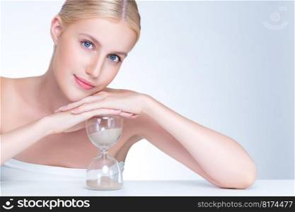 Personable model holding hourglass in beauty concept of anti-aging skincare treatment for woman. Young girl portrait with perfect smooth clean skin and flawless soft makeup in isolated background.. Personable beautiful woman with hourglass as anti-aging skincare concept