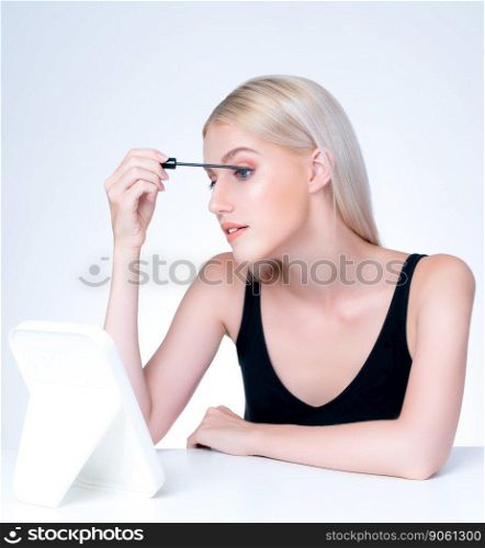 Personable woman with blond hair putting black mascara with brush in hand on long thick eyelash. Perfect fashionable cosmetic clean facial skin with beautiful eye young woman in high resolution.. Personable beautiful woman putting alluring black mascara eyelashes.