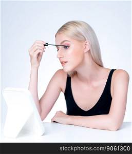 Personable woman with blond hair putting black mascara with brush in hand on long thick eyelash. Perfect fashionable cosmetic clean facial skin with beautiful eye young woman in high resolution.. Personable beautiful woman putting alluring black mascara eyelashes.