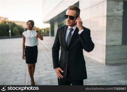 Personal bodyguard in sunglasses and black business woman. Security guard is a risky profession, guarding. Bodyguard in sunglasses and black business woman