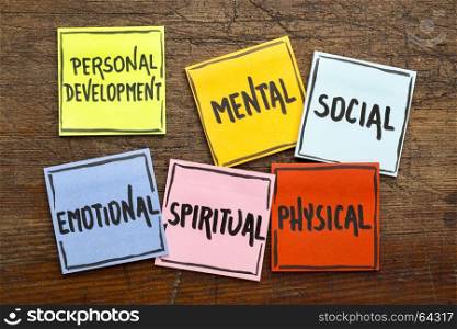 personal development concept (mental, social, emotional, spiritual, physical) - handwriting in black ink on sticky notes against rustic wood