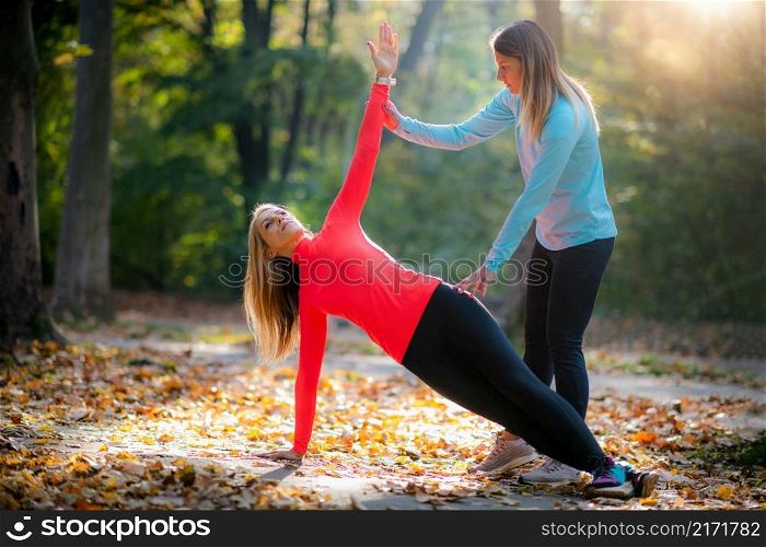 Personal Fitness Trainer Using Smart Watch During Training in the Park. Woman Doing Plank.. ersonal Fitness Trainer Using Smart Watch During Training in the Park.
