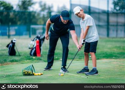 Personal golf lesson. Golf instructor with young boy on a golf driving range.