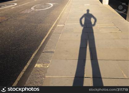 Personal perspective shadow of a man putting hands on his hips at sunset leaving the office