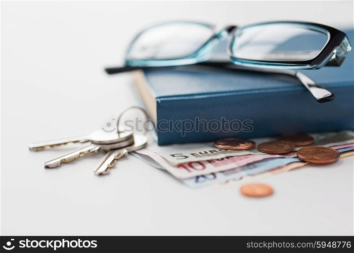 personal stuff and objects concept - close up of book, money, glasses and keys on table