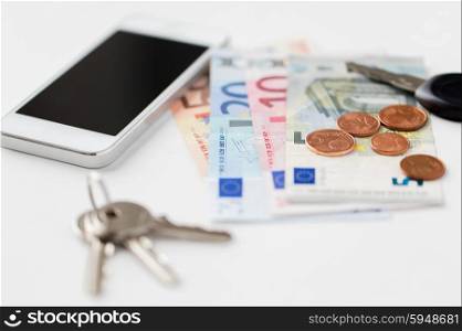 personal stuff and objects concept - close up of smartphone, euro money and keys on table