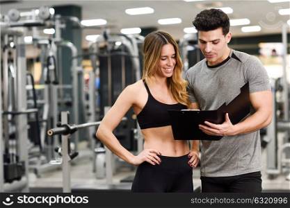Personal trainer and client looking at her progress at the gym. Athletic man and woman wearing sportswear.