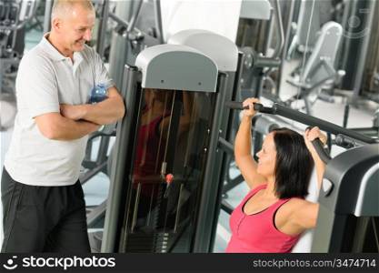 Personal trainer at fitness center showing exercise to active man