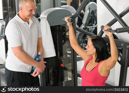 Personal trainer at fitness center showing exercise to active man