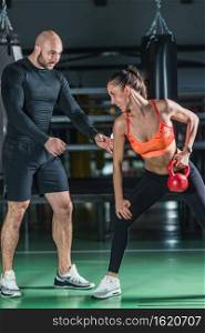Personal trainer exercising with kettlebell with woman in the gym