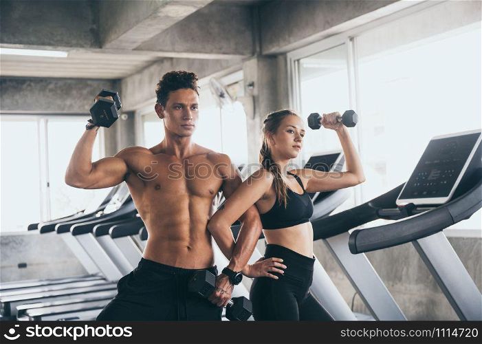 Personal trainer helping woman exercising in the sport gym