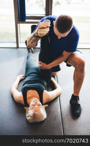 Personal trainer helping woman in stretching exercises. Gym instructor.. Personal trainer helping woman in stretching