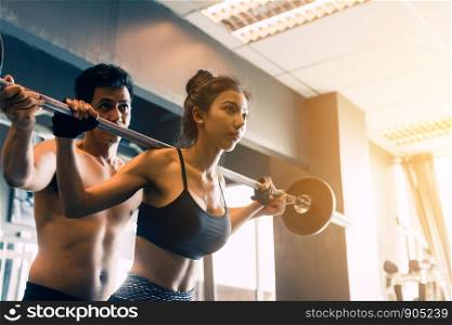 Personal trainer helping women and handle heavy barbells two hand top a shoulder.