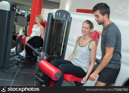 personal trainer helping women working out in gym