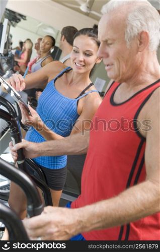 Personal Trainer Instructing Man On Treadmill