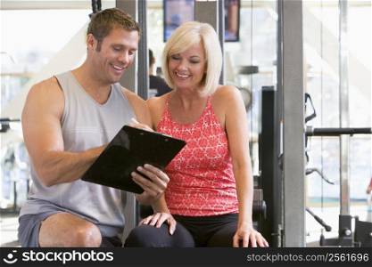 Personal Trainer Talking To Woman At Gym