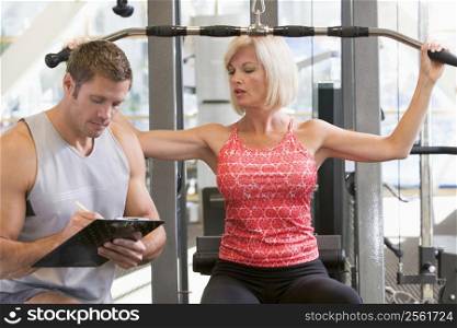 Personal Trainer Watching Woman Weight Train
