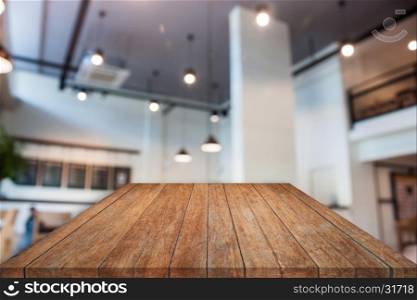 Perspective brown wooden table top with abstract blur coffee shop interior for background