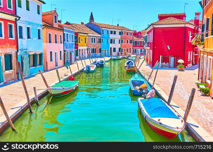 Perspective of a canal with boats and colorful houses in Burano, Venice, Italy