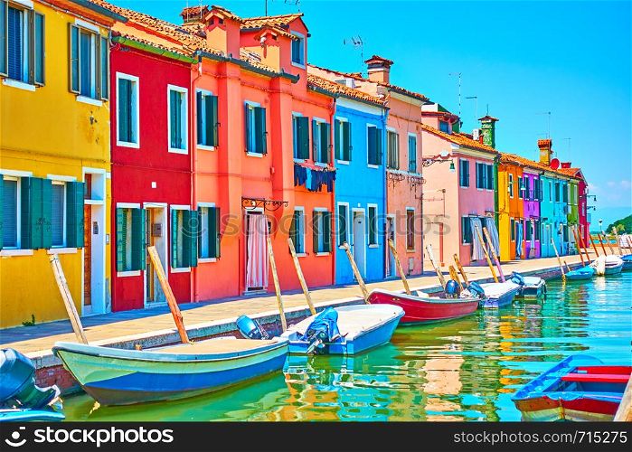 Perspective of canal with boats and picturesque houses in Burano on summer sunny day, Venice, Italy