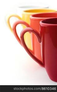 Perspective row of bright colorful mugs, red, orange, yellow and white, on a white background. Bright mugs