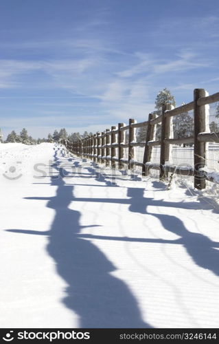 Perspective shot of post rail fence line shadows in the freshily fallen snow.