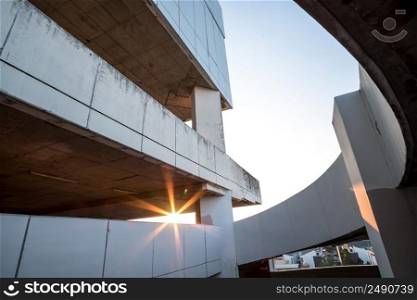 Perspective view of a circular car parking garage against the sun setting and sky. Automated circular parking system. Architecture, structure. Selective focus.