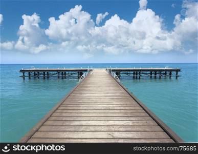 Perspective view of a wooden pier on the seashore with clear blue sea