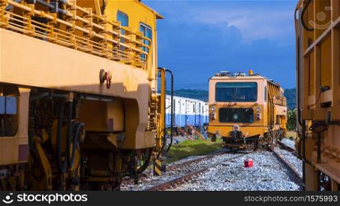 Perspective view of the old orange diesel locomotives parking on railway at train garage against blue sky in natural background