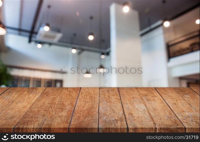 Perspective wooden table top with abstract blur coffee shop interior for background