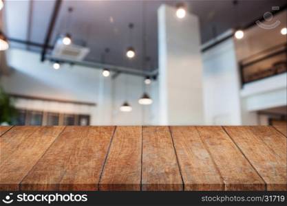 Perspective wooden table top with abstract blur coffee shop interior for background