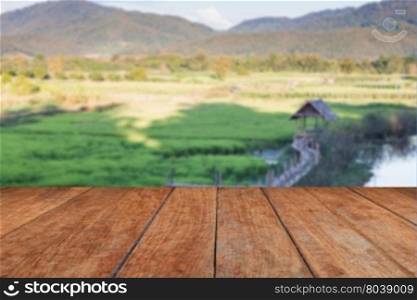 Perspective wooden with green rice field blurred background, stock photo
