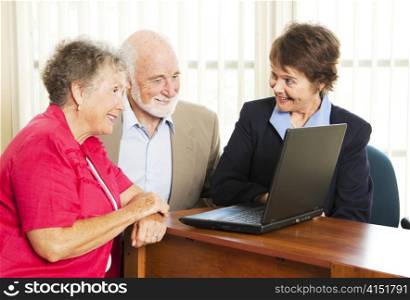 Persuasive sales woman pitches financial services to an elderly couple.