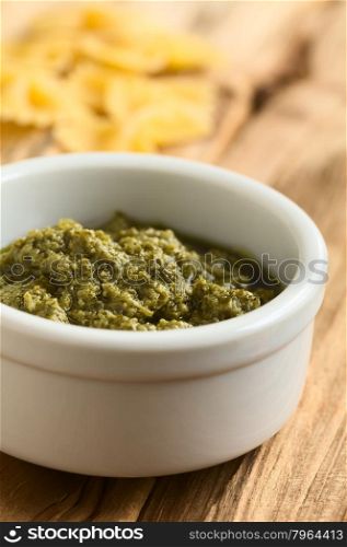 Pesto alla genovese made of basil, garlic, olive oil, pine nuts and cheese, traditional sauce for pasta in the Italian cuisine, photographed on wood with natural light (Selective Focus, Focus one third into the pesto)
