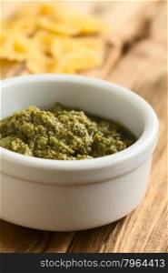 Pesto alla genovese made of basil, garlic, olive oil, pine nuts and cheese, traditional sauce for pasta in the Italian cuisine, photographed on wood with natural light (Selective Focus, Focus one third into the pesto)