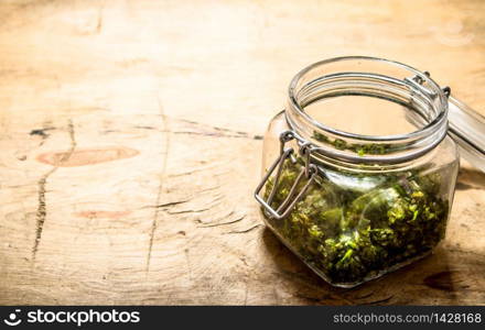 Pesto in a glass jar. On a wooden table.. Pesto in a glass jar.