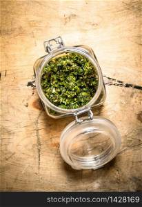 Pesto in a glass jar. On a wooden table.. Pesto in a glass jar.