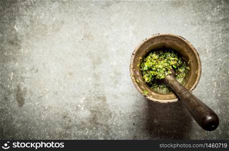 Pesto in a mortar with pestle. On the stone table.. Pesto in a mortar with pestle.
