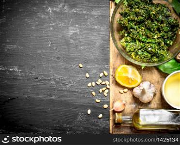 Pesto sauce with olive oil, garlic and other ingredients. On the black wooden table.. Pesto sauce with olive oil, garlic and other ingredients.