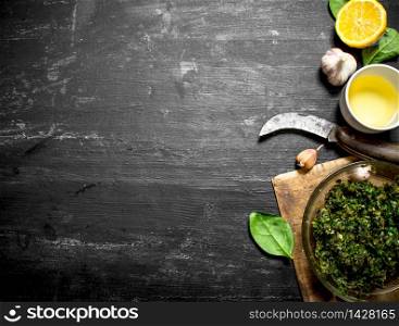 Pesto sauce with olive oil, garlic and other ingredients. On the black wooden table.. Pesto sauce with olive oil, garlic and other ingredients.