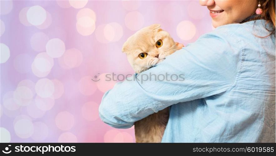 pet, animals, care and people concept - close up of happy woman holding scottish fold kitten over pink holidays lights background