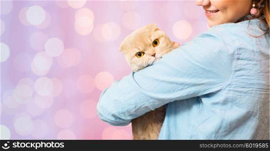 pet, animals, care and people concept - close up of happy woman holding scottish fold kitten over pink holidays lights background