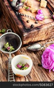 petals of tea-rose for tea. Dry rose buds tea.Tea strainer and rosebuds on a wooden background