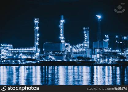 Petrochemical oil refinery and sea in industrial engineering concept in Bangna district, Bangkok, Thailand. Oil and gas tanks pipelines in industry. Modern metal factory at night.