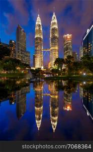 Petronas Twin Towers in Kuala Lumpur Downtown with reflection, Malaysia. Financial district and business centers in smart urban city in Asia. Skyscraper and high-rise buildings at night.
