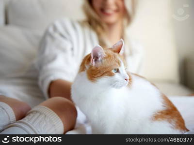 pets, animals and people concept - happy young woman with cat in bed at home