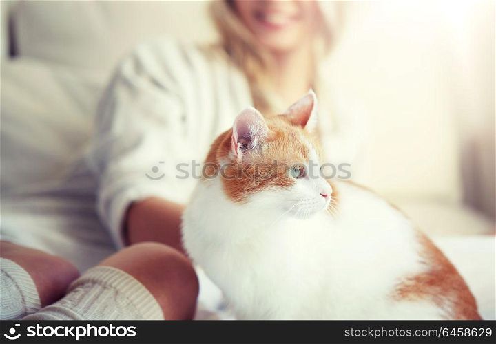 pets, animals and people concept - happy young woman with cat in bed at home. happy young woman with cat in bed at home