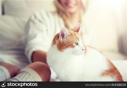pets, animals and people concept - happy young woman with cat in bed at home. happy young woman with cat in bed at home