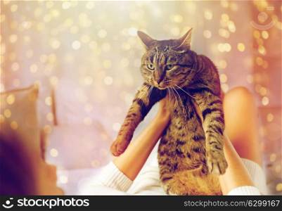 pets, comfort, christmas, winter and people concept - young woman with cat lying in bed at home. young woman with cat lying in bed at home