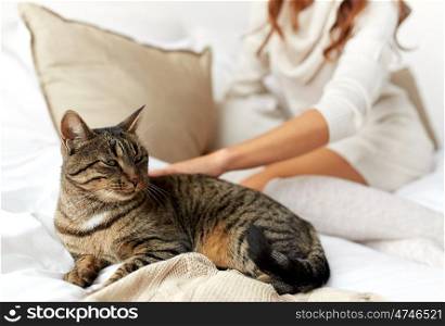 pets, comfort, rest and people concept - young woman with cat in bed at home